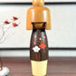 kokeshi, poupée japonaise en bois de Usaburo, avec 3 essences de bois de couleurs différentes et motif fleur de prunier