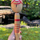 kokeshi poupée japonaise aux grands yeux cernés de rose et à l'expression étonnée, vu de dos