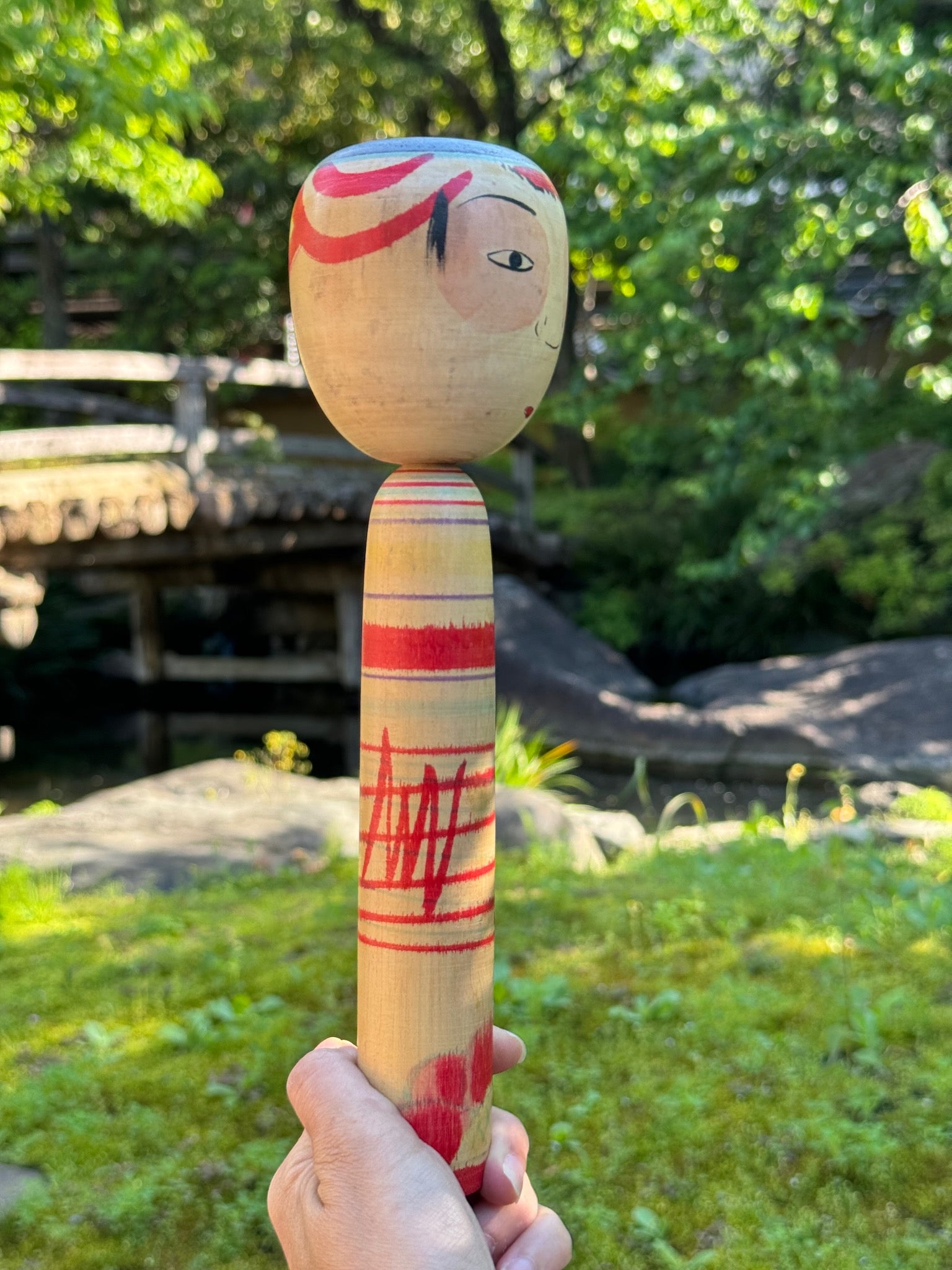 kokeshi poupée japonaise aux grands yeux cernés de rose et à l'expression étonnée, profil droit