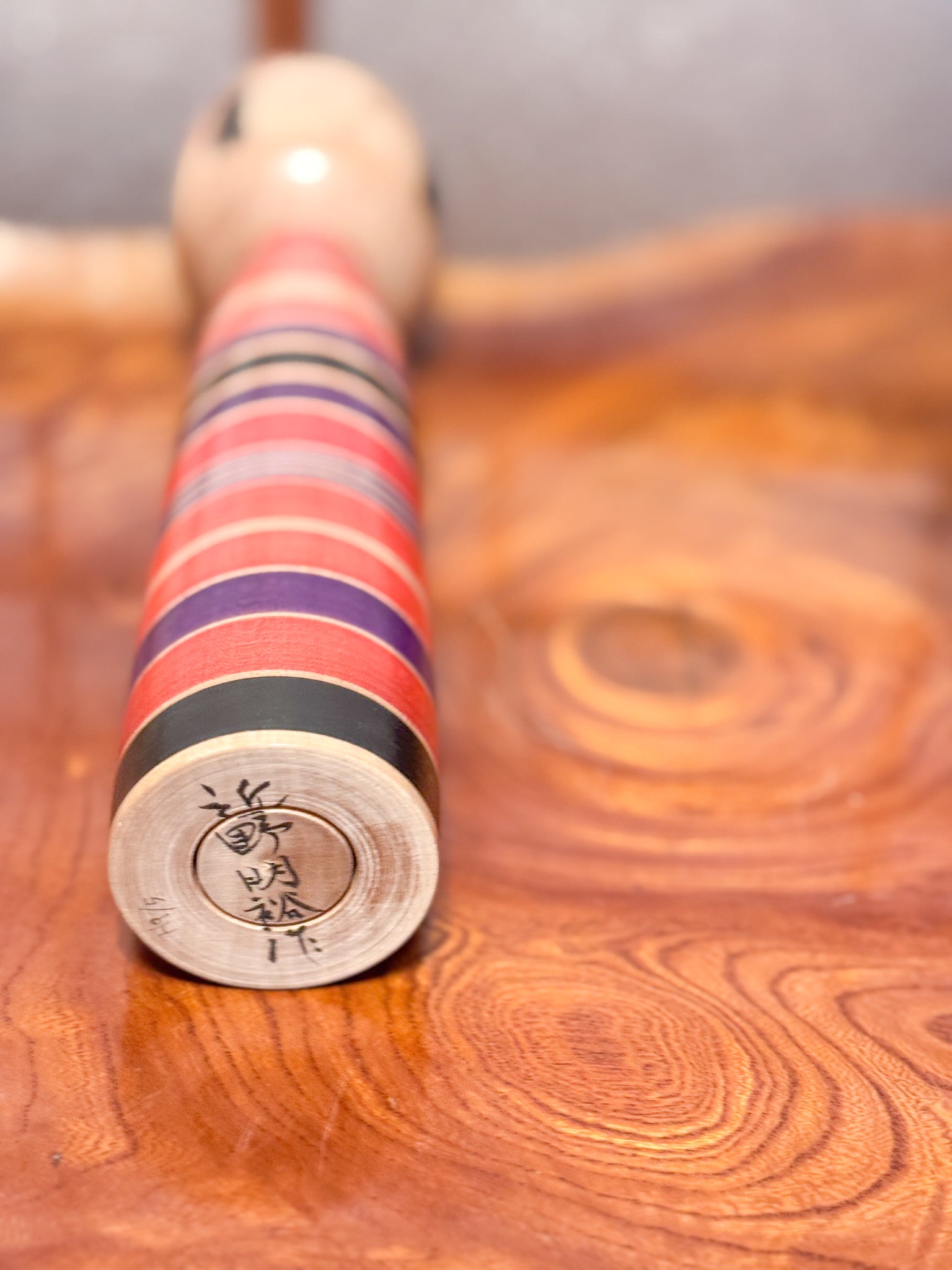 Kokeshi traditionnelle rayures noires rouges et violettes vue dessous