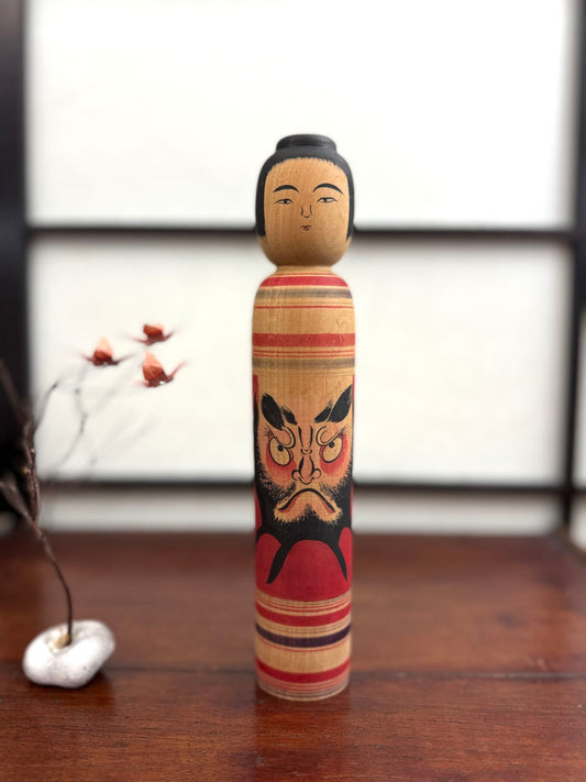 Kokeshi vintage Junichi Sasamori style Kohei avec visage de Daruma rouge et noir, de face.