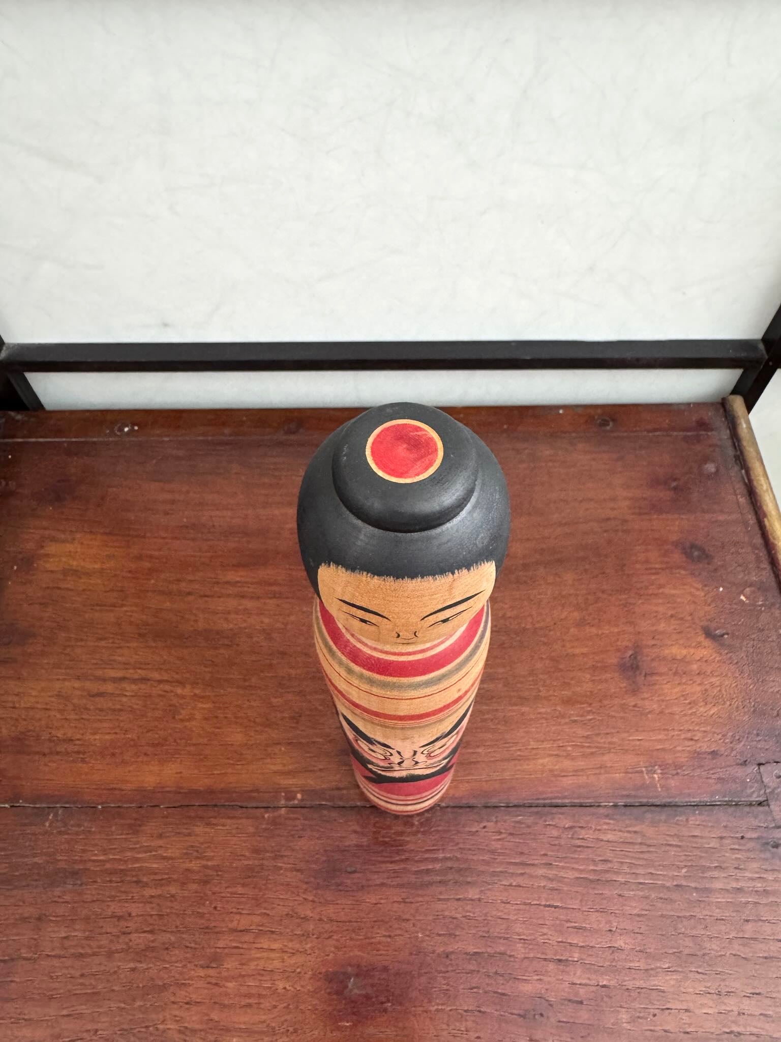 Kokeshi vintage Junichi Sasamori style Kohei avec visage de Daruma rouge et noir, vu de dessus
