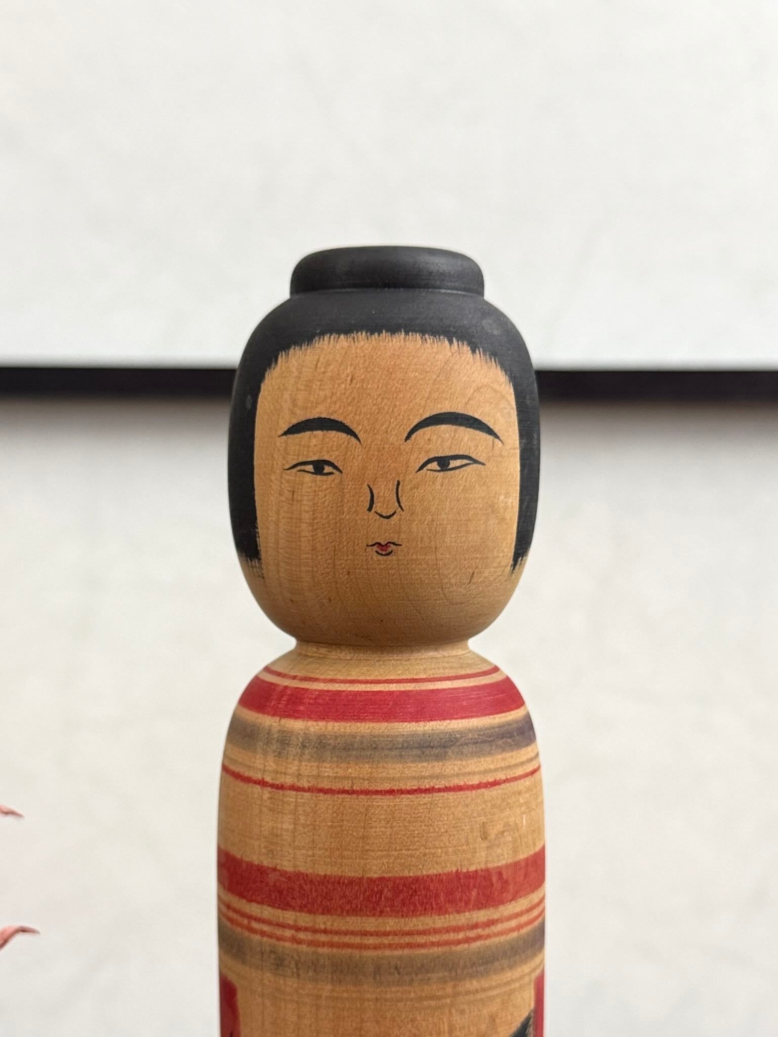 Kokeshi vintage Junichi Sasamori style Kohei avec visage de Daruma rouge et noir, gros plan sur le visage de la kokeshi