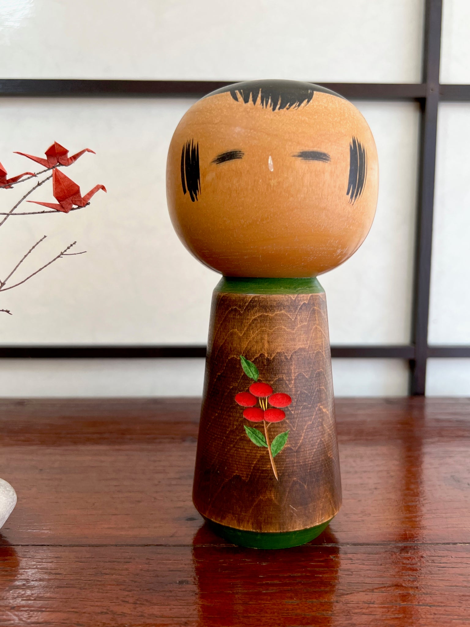 kokeshi, poupée traditionnelle japonaise en bois avec une fleur de camélia rouge gravée.