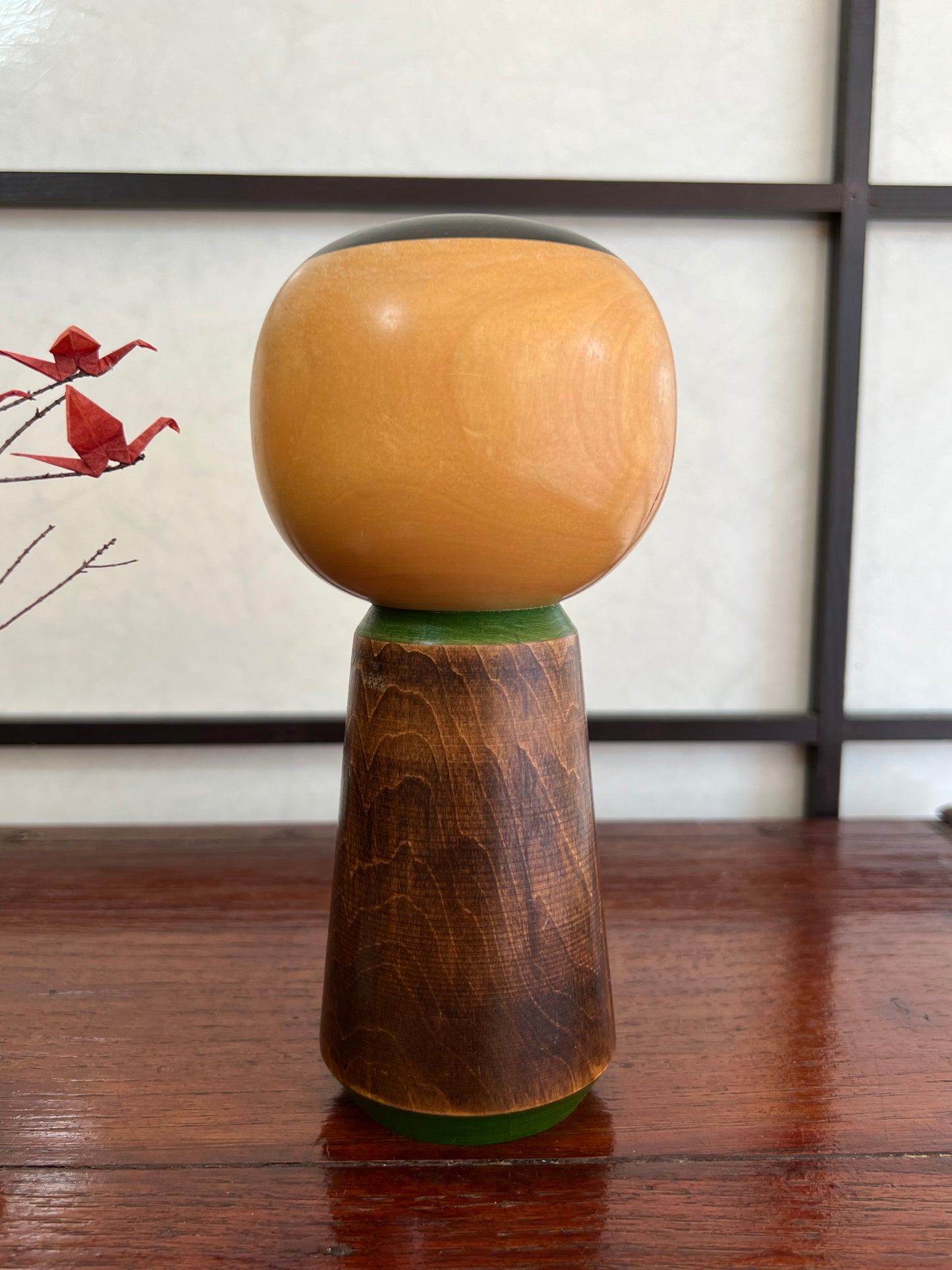 kokeshi, poupée traditionnelle japonaise en bois avec une fleur de camélia rouge gravée, profil droit, vu de dos