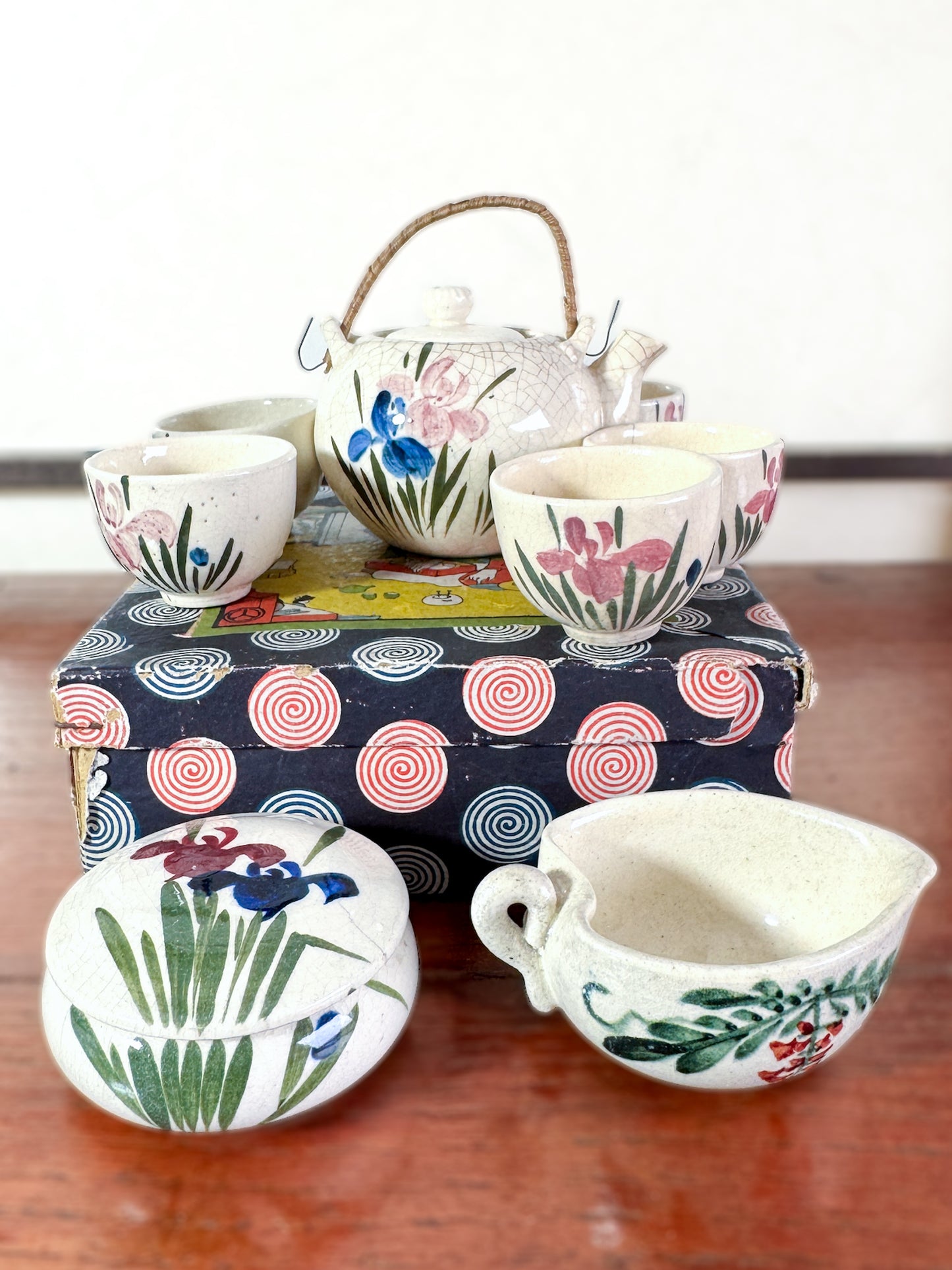 Service à thé miniature japonais vintage avec motifs d’iris, posé sur la boîte imprimée spirales et scène de cérémonie du thé