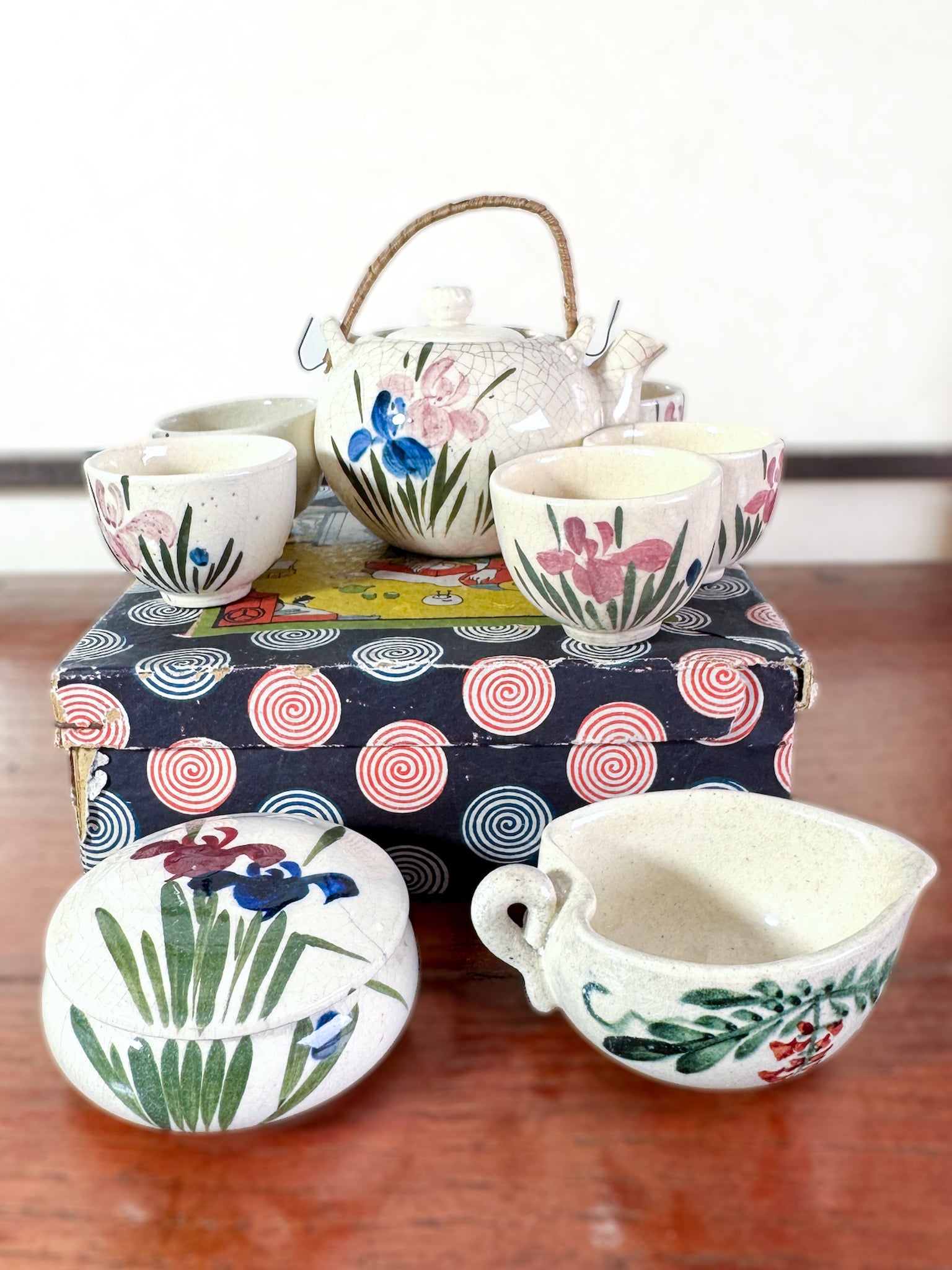 Service à thé miniature japonais vintage avec motifs d’iris, posé sur la boîte imprimée spirales et scène de cérémonie du thé