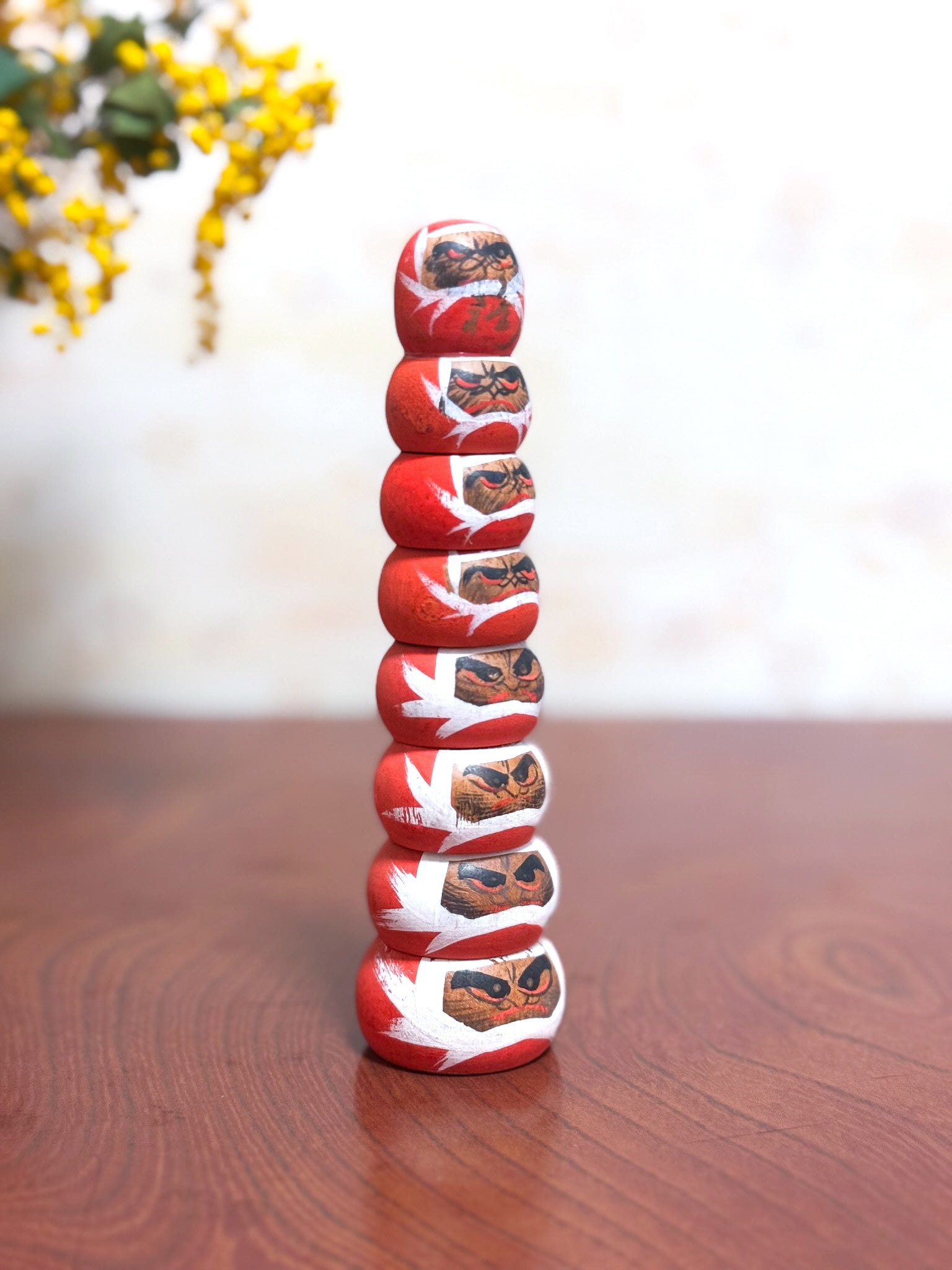 kokeshi de huit daruma empilé en tour, vu de profil