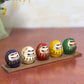 Ensemble de cinq Daruma colorés sur socle en bois