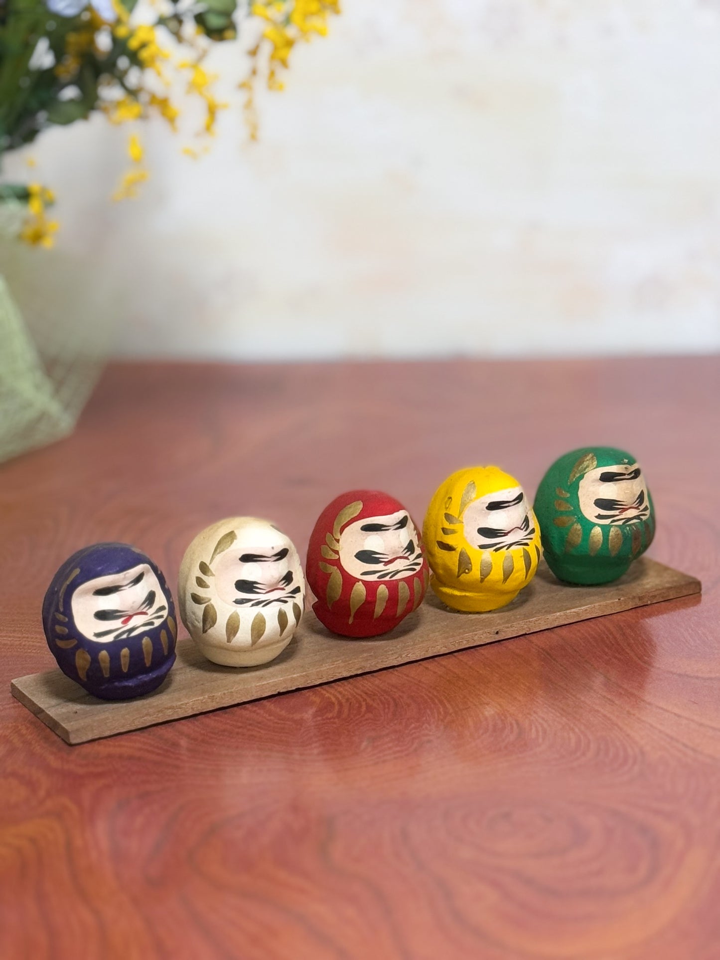 Ensemble de cinq Daruma colorés sur socle en bois
