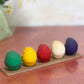 Ensemble de cinq Daruma colorés sur socle en bois