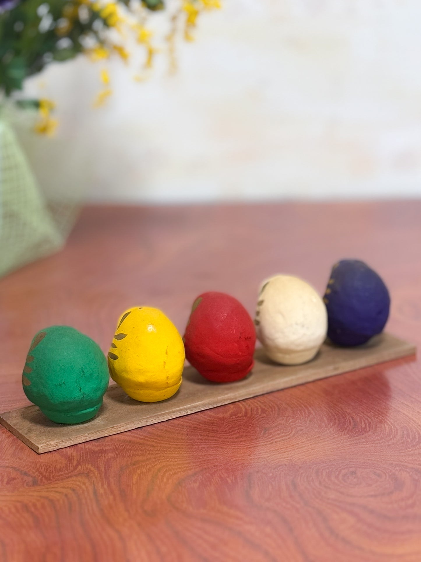 Ensemble de cinq Daruma colorés sur socle en bois