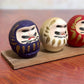 Ensemble de cinq Daruma colorés sur socle en bois