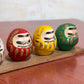 Ensemble de cinq Daruma colorés sur socle en bois