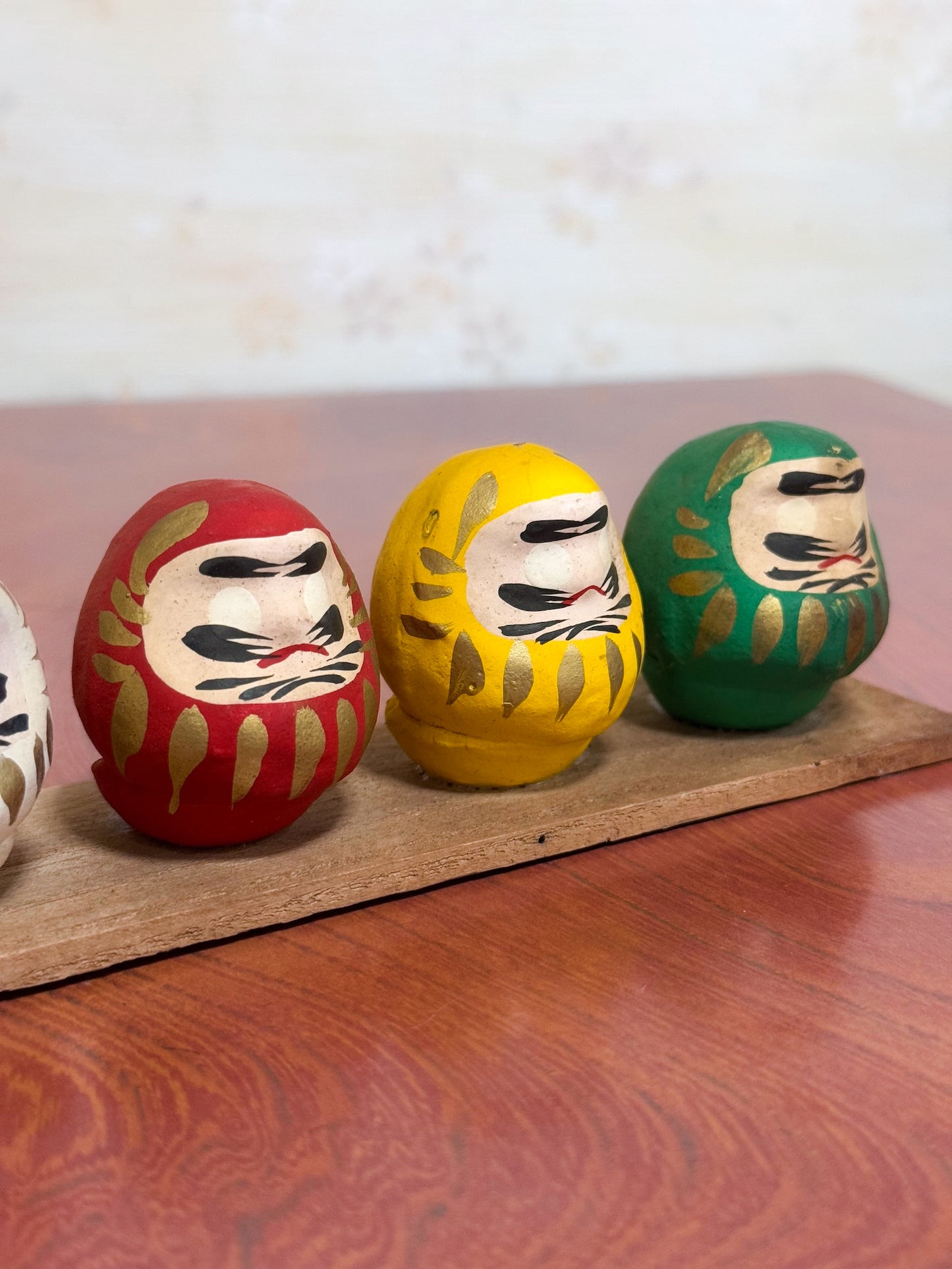 Ensemble de cinq Daruma colorés sur socle en bois