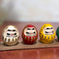 Ensemble de cinq Daruma colorés sur socle en bois