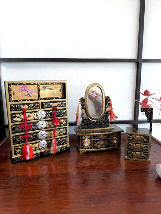 Ensemble de mobilier miniature japonais en laque noire, avec commode, coiffeuse à miroir et petit meuble à couture décorés d'arabesques et de fleurs dorées