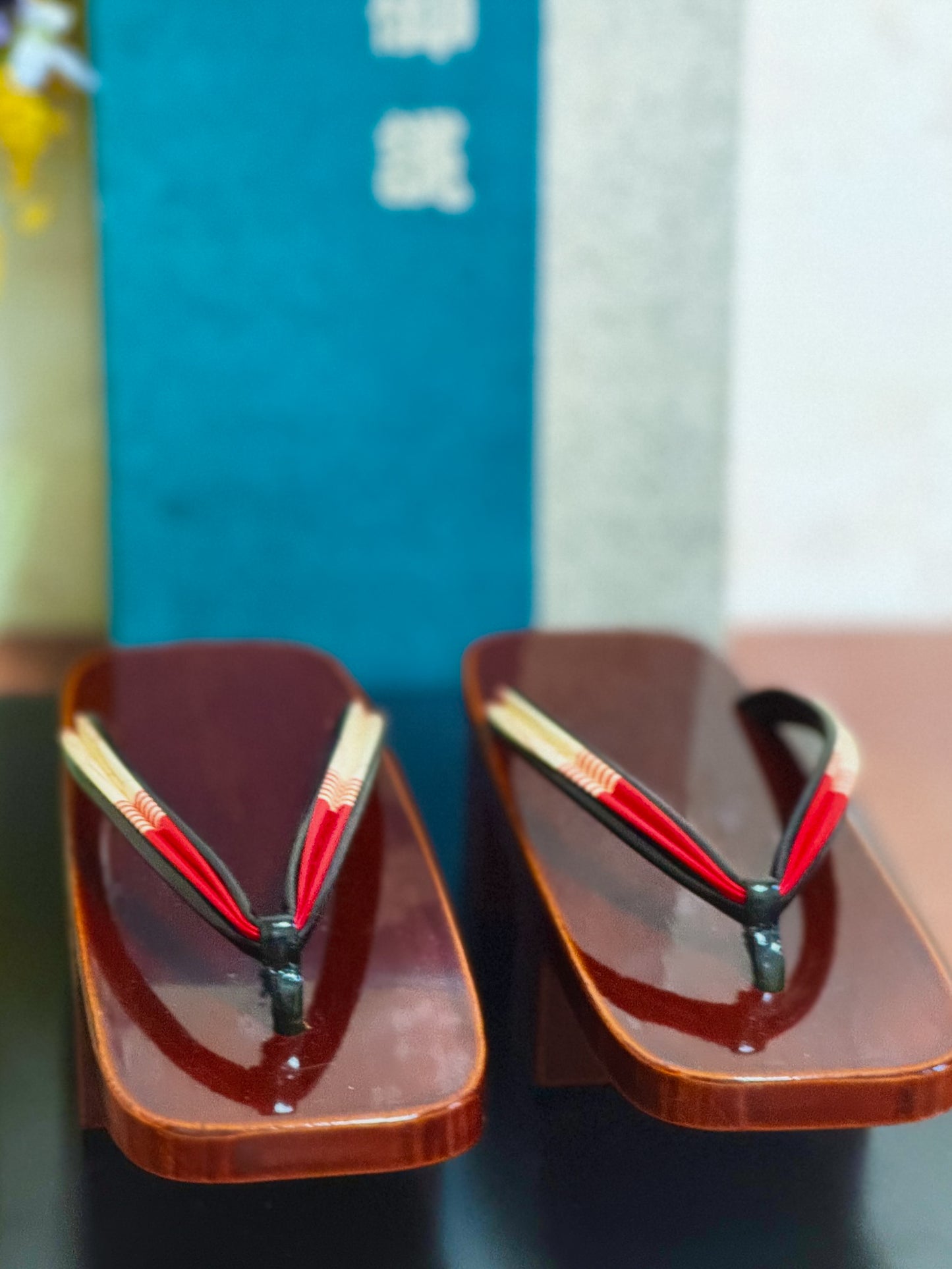 Paire de sandales geta japonaises en bois laqué brun avec lanières rouges et blanches, profil