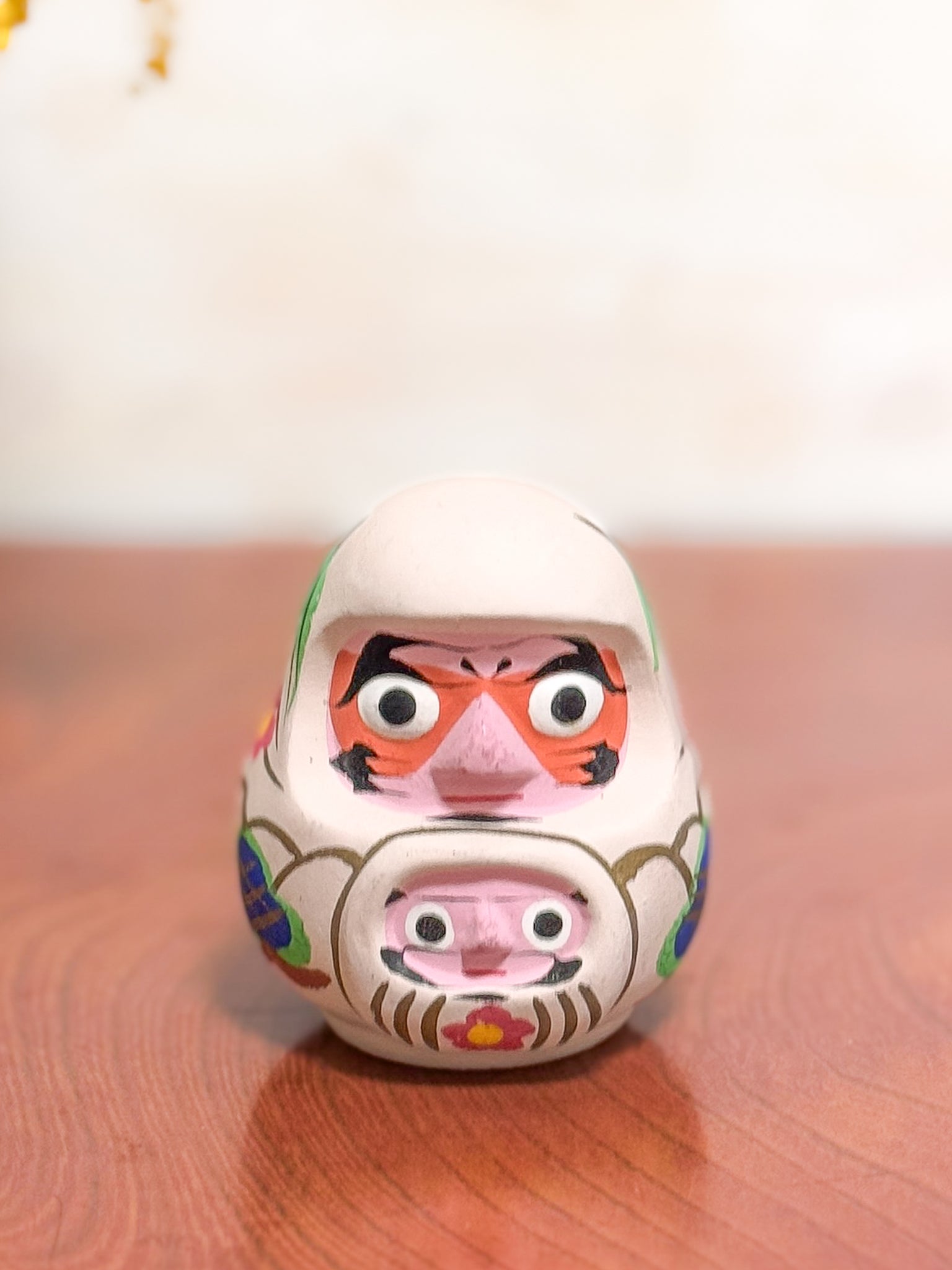Clochette japonaise en terre cuite peinte à la main représentant deux daruma, adulte et enfant, ornée de fleurs et motifs traditionnels, vu de face