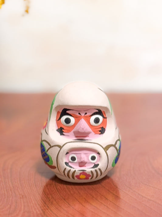 Clochette japonaise en terre cuite peinte à la main représentant deux daruma, adulte et enfant, ornée de fleurs et motifs traditionnels, vu de face