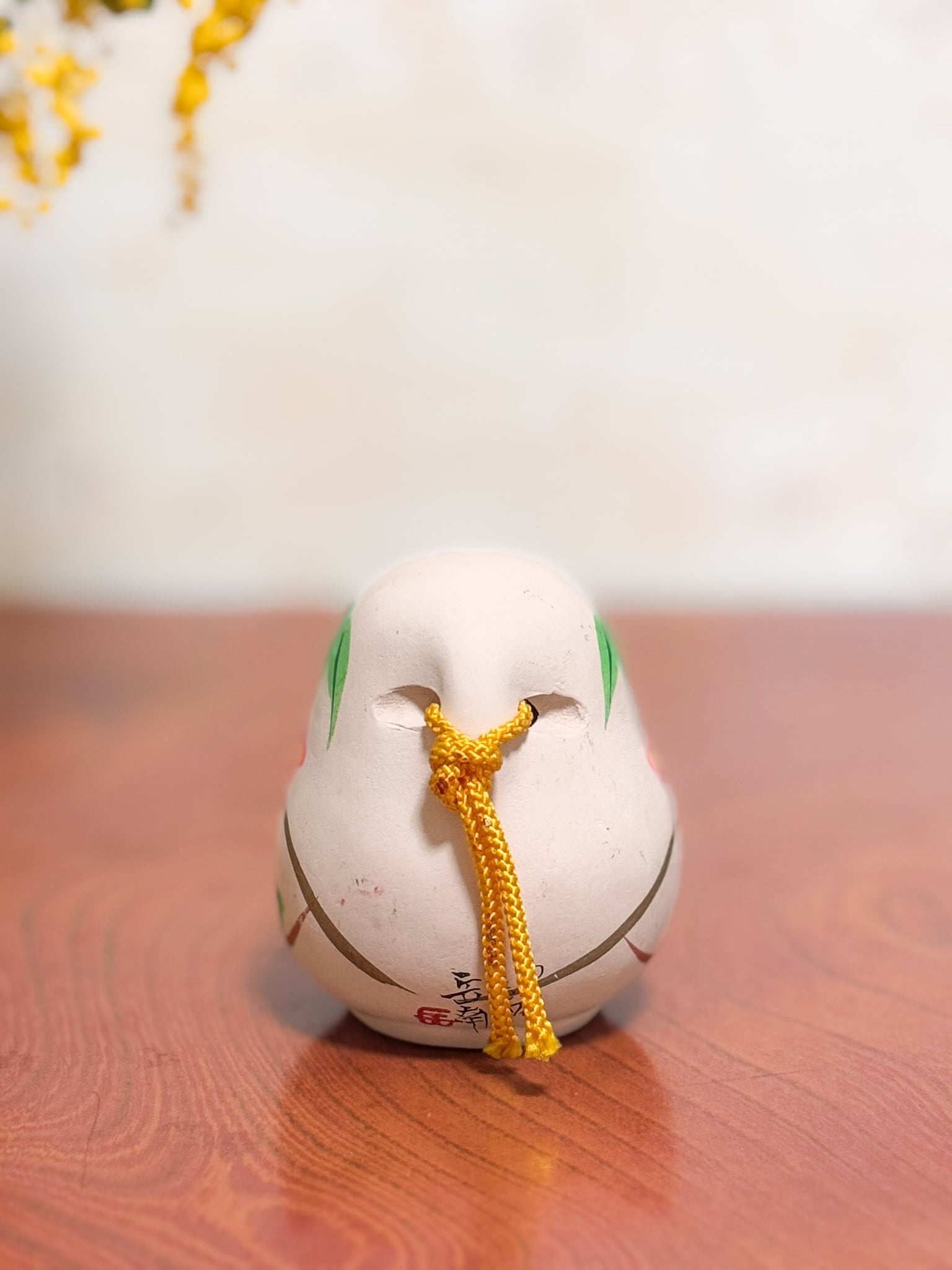 Clochette japonaise en terre cuite peinte à la main représentant deux daruma, adulte et enfant, ornée de fleurs et motifs traditionnels, vu de dos
