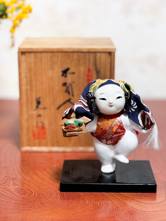 Figurine japonaise Gosho Ningyō représentant un enfant dansant avec une tête de lion Shishimai, sur socle laqué, avec boîte en bois calligraphiée