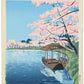 Estampe japonaise de tokuriki tomikichiro, la rive au bord du temple daikakuji à saga kyoto. Un bateau est amarré sous un grand cerisier en fleurs. 