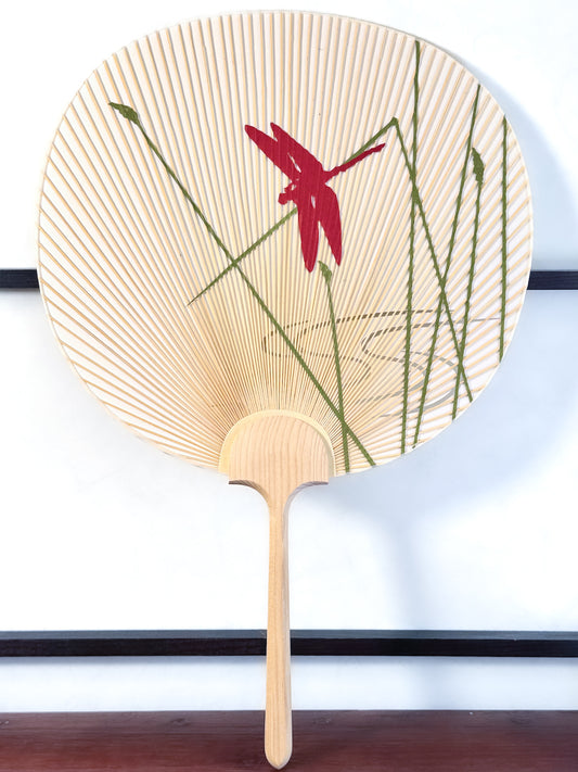 éventail uchiwa japonais avec libellule rouge, herbes vertes et ruisseau découpé dans le papier, recto