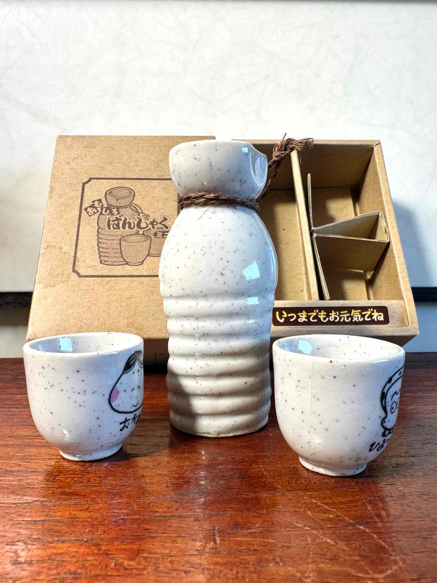 service saké japonais coffret okame hyottoko céramique, pichet et deux tasses vu de dos