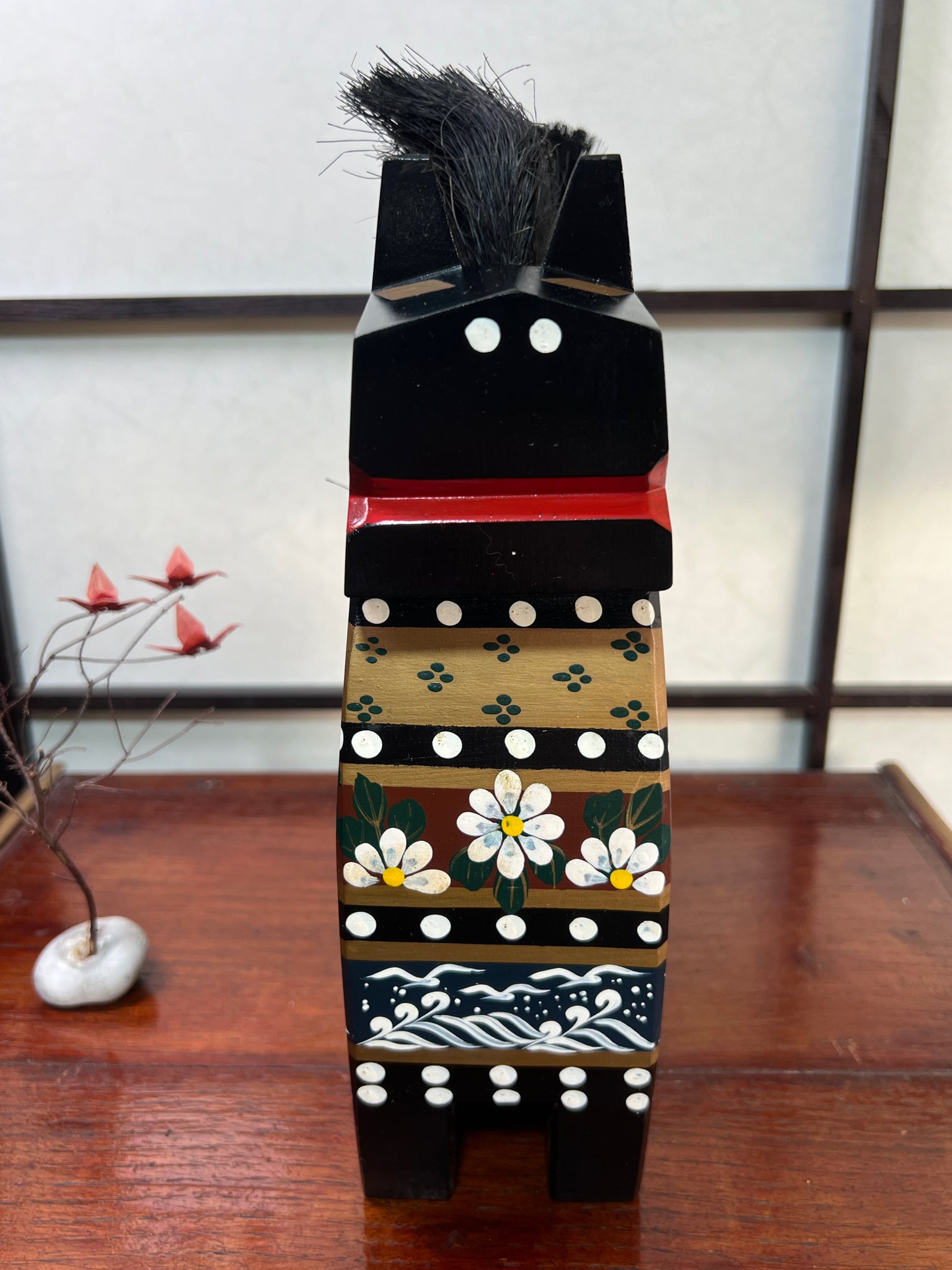 cheval traditionnel japonais en bois noir de face, bouche rouge et peinture sur poitrail fleur vagues et oiseaux