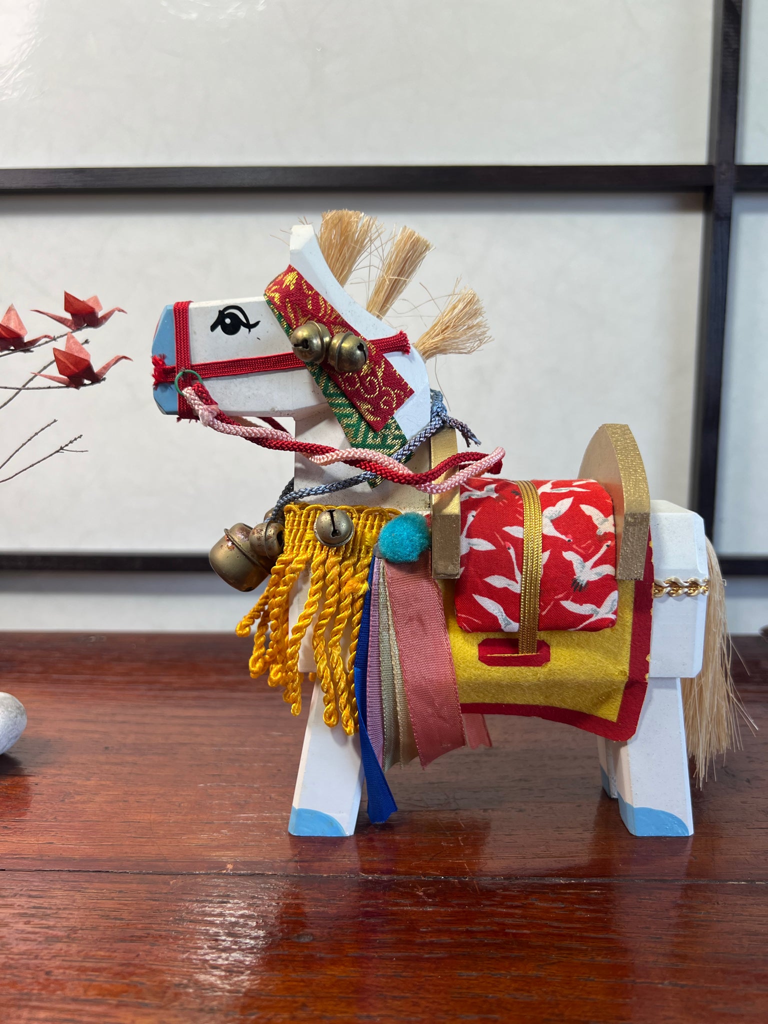cheval en bois blanc parures jaune et rouge, de profil, selle tissus de kimono grues