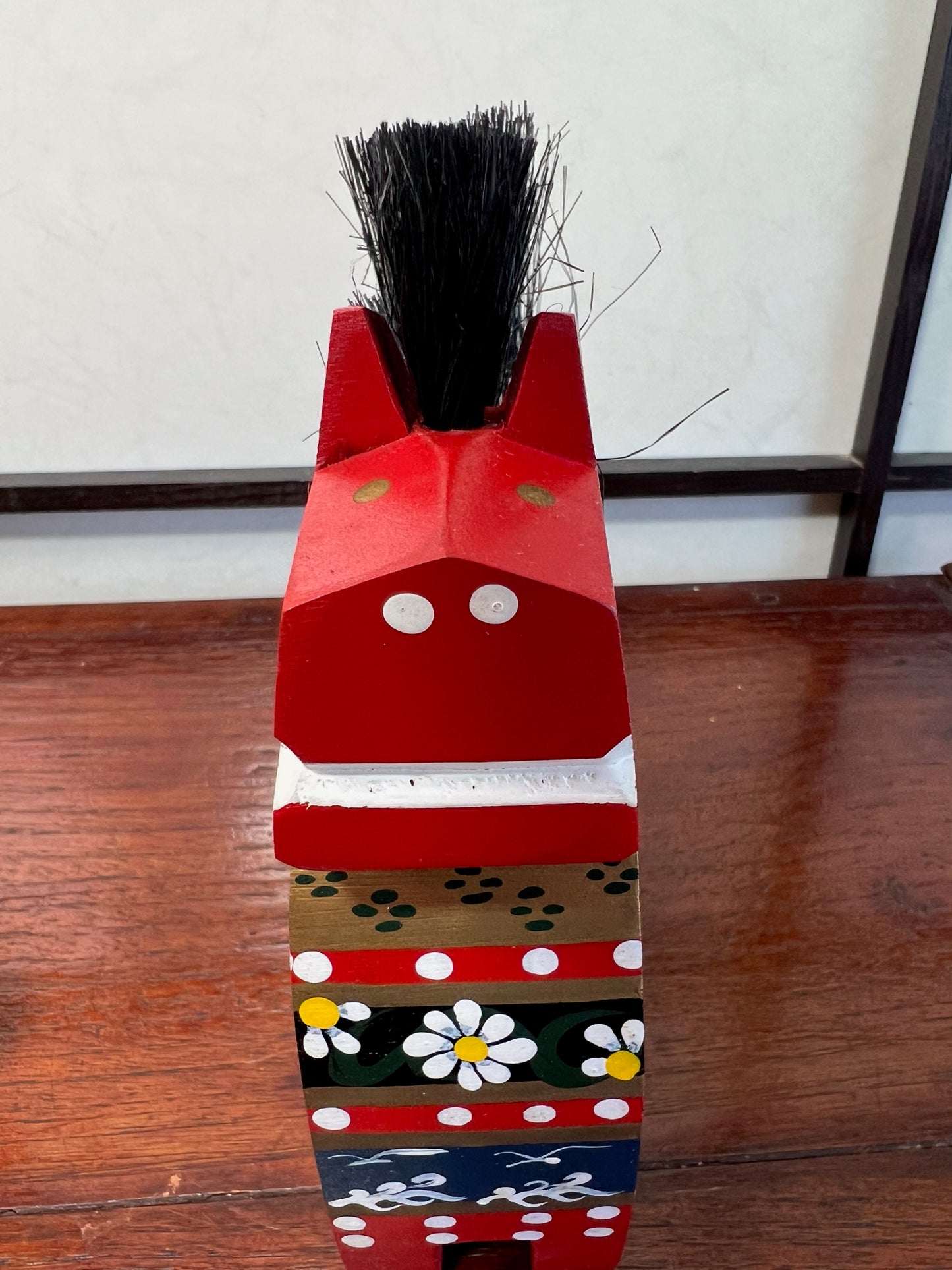 Cheval traditionnel en bois rouge de face en gros plan, bouche et naseaux blanc