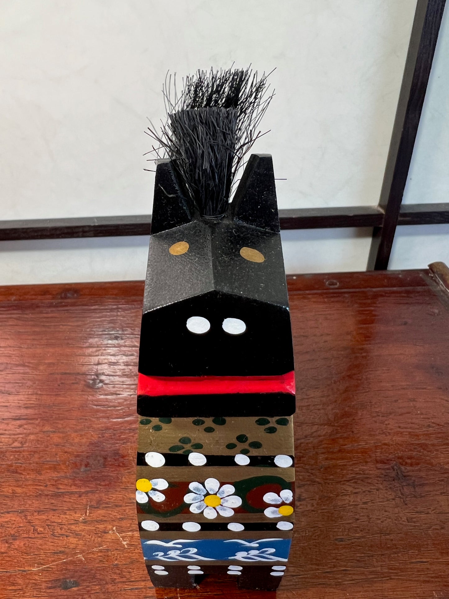 Cheval traditionnel japonais en bois noir gros plan de face, naseaux blancs et bouche rouge