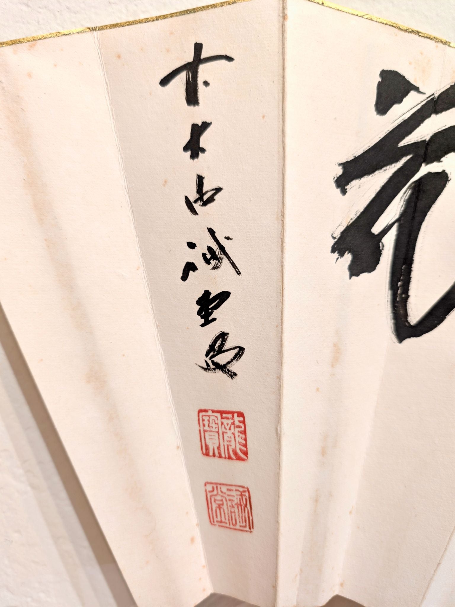 Éventail japonais en papier calligraphié avec les kanji fleur, lune, neige, gros plan sur calligraphie et sceaux rouges