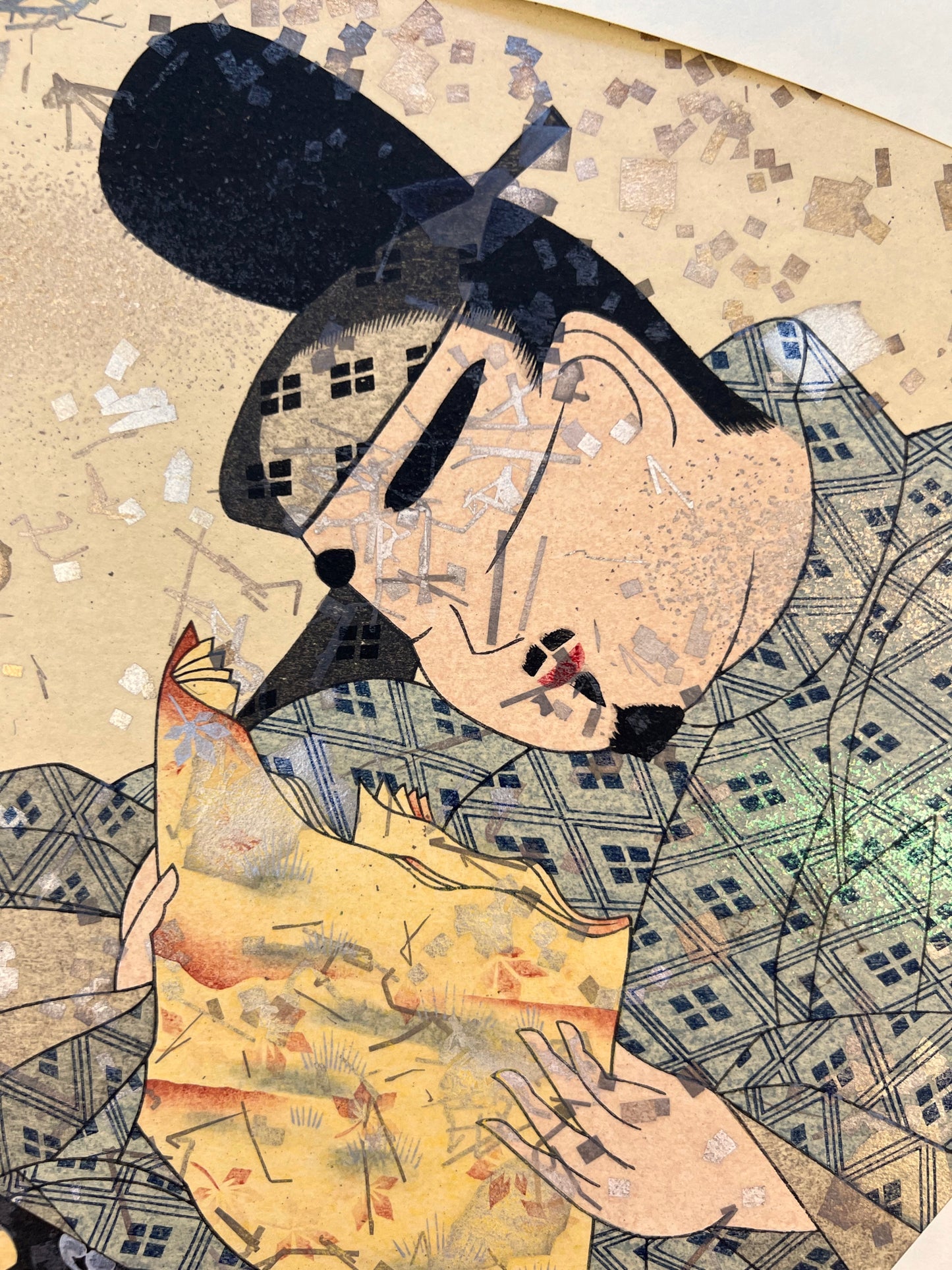 estampe japonaise en forme d'éventail parsemé de fragment d'or et d'argent, un homme lit un poème à une femme agenouillée, gros plan sur le visage de l'homme