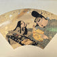 estampe japonaise en forme d'éventail parsemé de fragment d'or et d'argent, un homme lit un poème à une femme agenouillée.