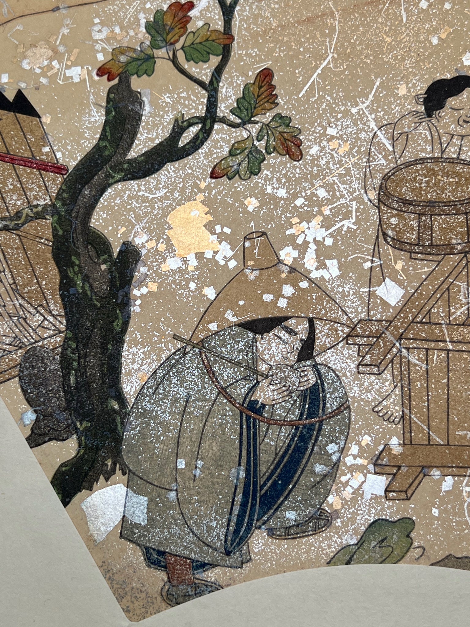 Estampe japonaise en forme d'éventail parsemée de fragments d'or et d'argent, gros plan femme qui boit de l'eau avec une louche accroupie sous un chêne, feuilles d'automne, chapeau, puits.
