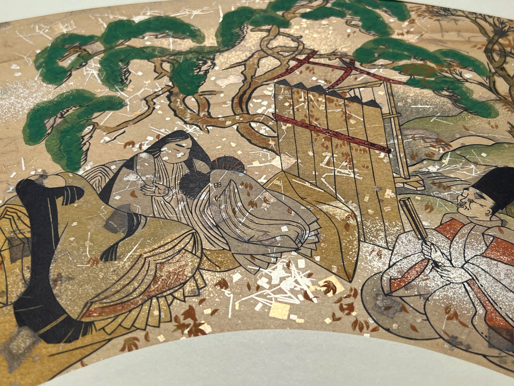 Estampe japonaise en forme d'éventail parsemée de fragments d'or et d'argent, deux femmes et un homme assis près d'un pin japonais, détail fragments scintillants.