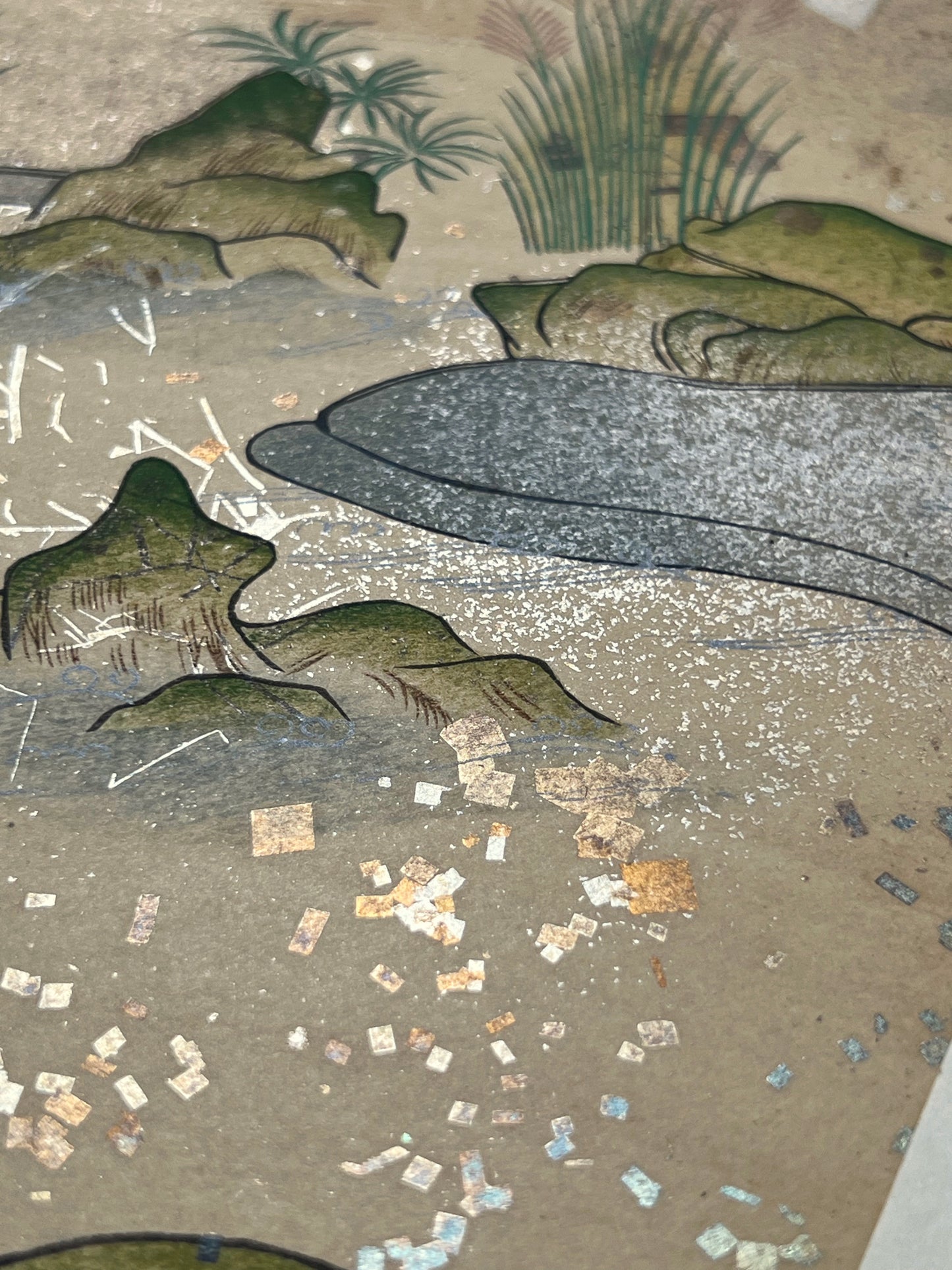 Estampe japonaise en forme d'éventail parsemée de fragments d'or et d'argent, gros plan sur l'eau de la rivière, herbes et rochers, fragments scintillants.