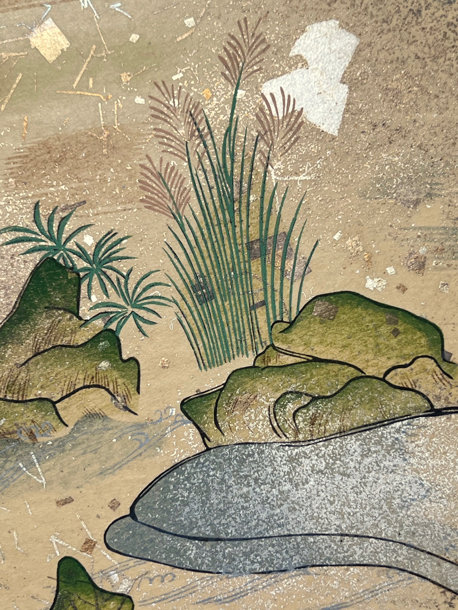 Estampe japonaise en forme d'éventail parsemée de fragments d'or et d'argent, gros plan sur les joncs épars au bord de la rivière, herbes et rochers, fragments scintillants.