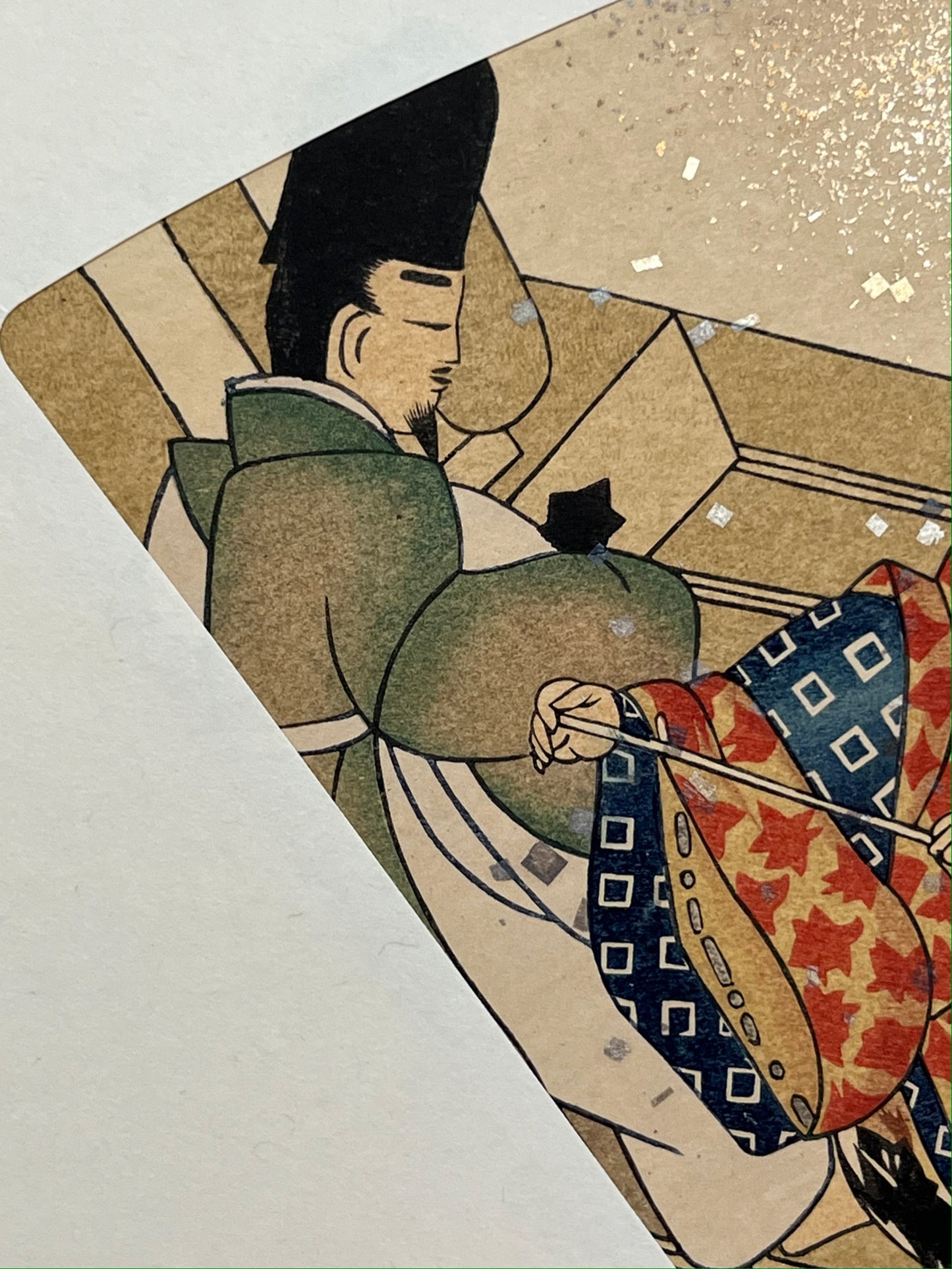 Estampe japonaise en forme d'éventail parsemée de fragments d'or et d'argent, gros plan sur un homme faisant le ménage sur la terrasse, main de l'autre homme tenant le manche d'une serpillère.