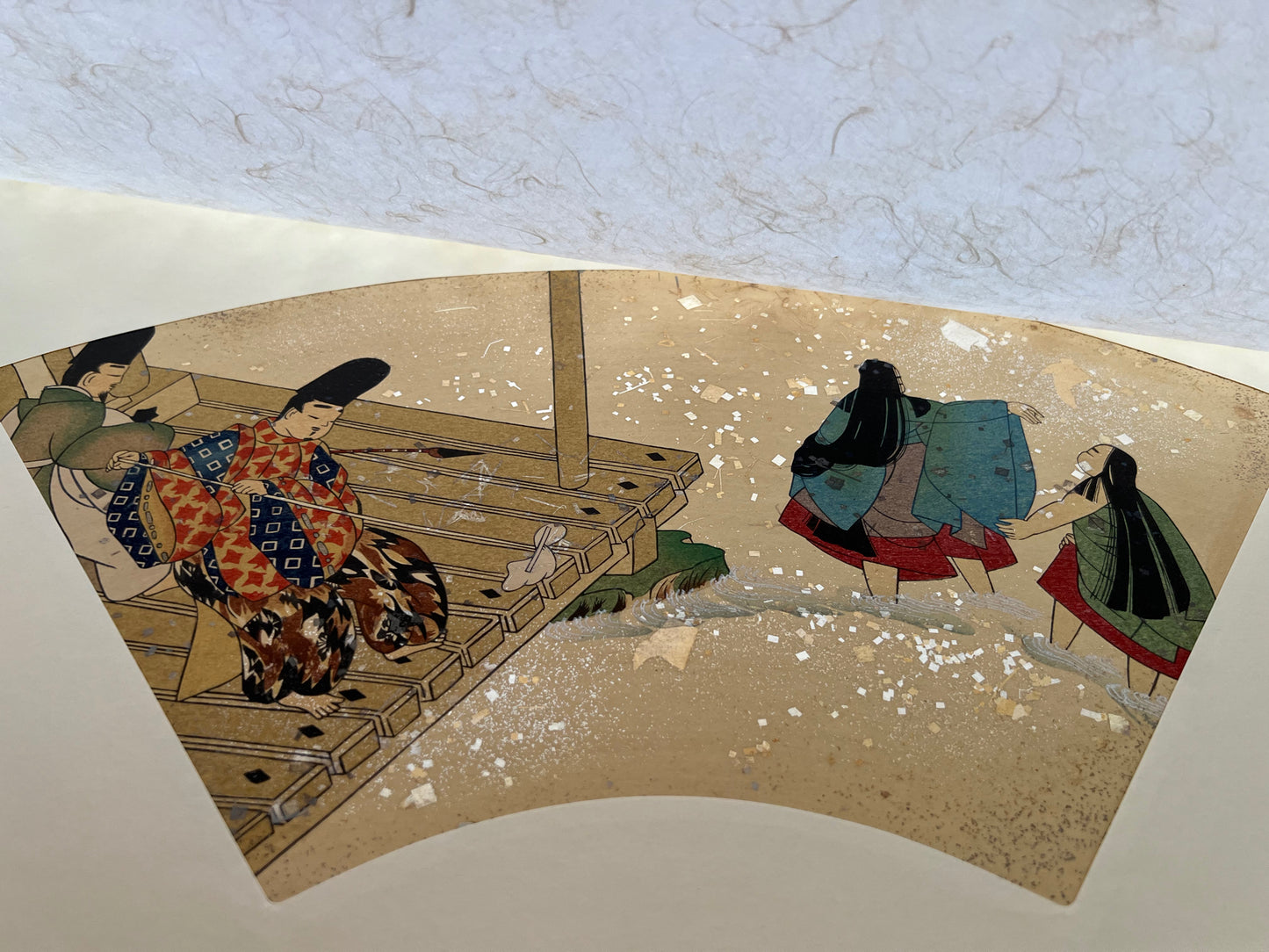 Estampe japonaise en forme d'éventail parsemée de fragments d'or et d'argent, deux hommes nettoient une terrasse au bord de l'eau pendant que deux femmes se baignent dans la rivière, série sutra du lotus, papier de protection.