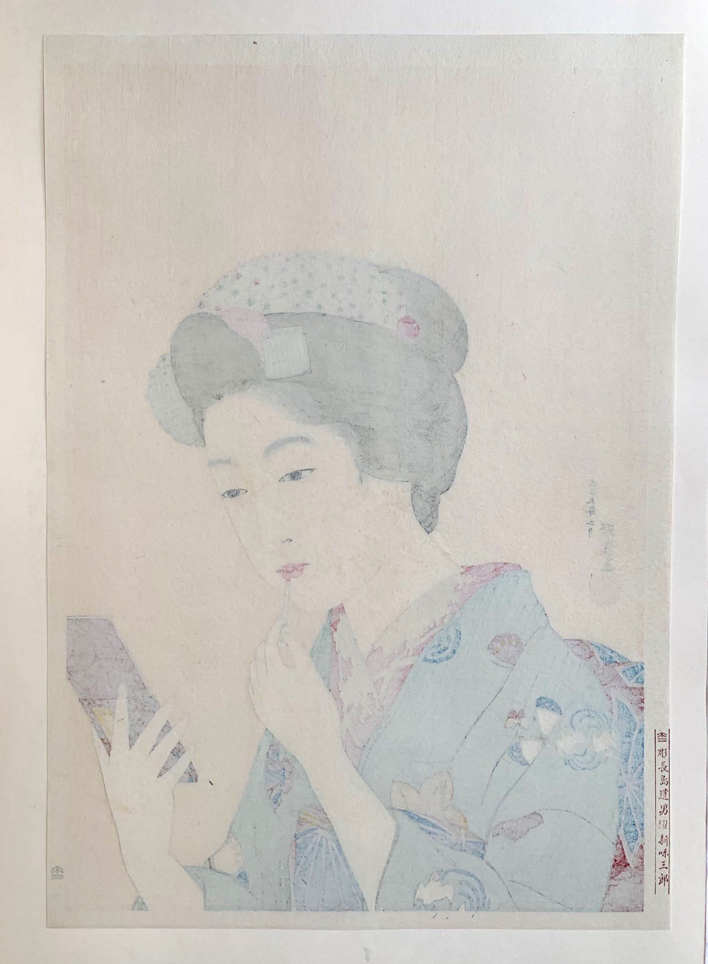 Estampe japonaise d’une femme se mettant du rouge à lèvre avec un pinceau, se regardant dans le miroir, portant un kimono vert., dos de l'estampe