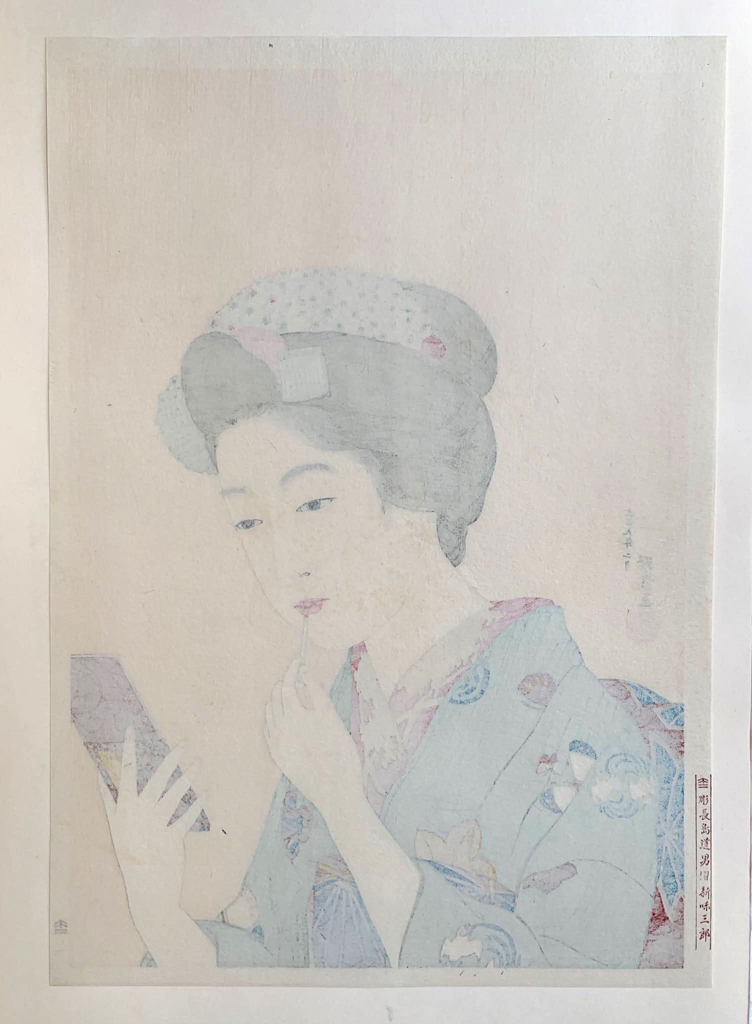 Estampe japonaise d’une femme se mettant du rouge à lèvre avec un pinceau, se regardant dans le miroir, portant un kimono vert., dos de l'estampe