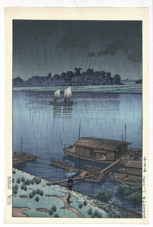estampe japonaise de Hasui, la rivière Arakawa de nuit sous une pluie de printemps, personnage sous un parapluie bleu en premier plan, bateau à voile en second plan
