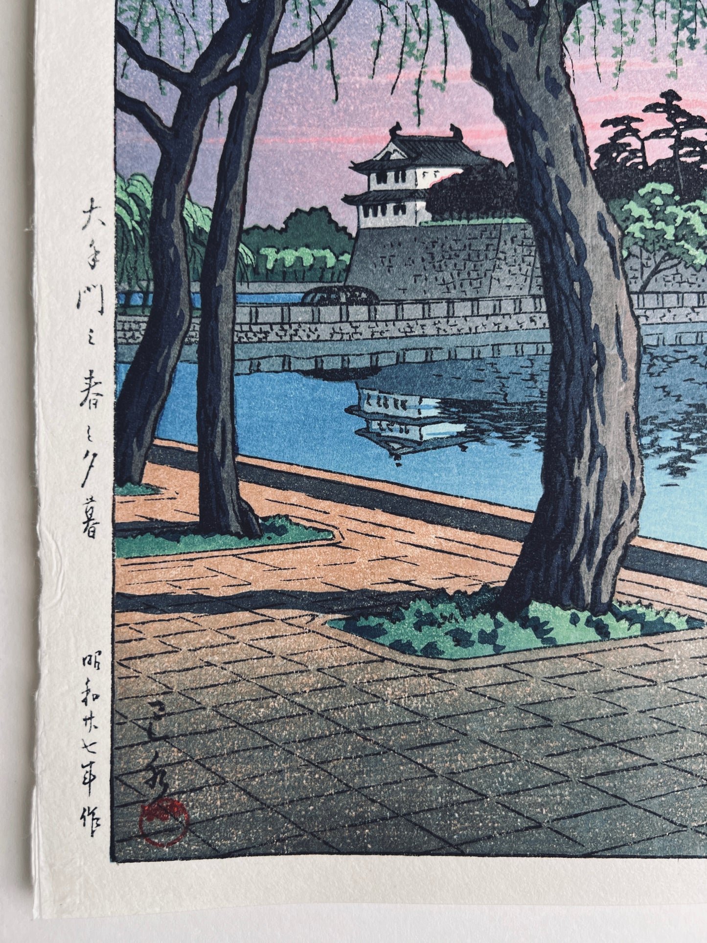 estampe japonaise lumière rose du soir sur le palais impérial de Tokyo, reflet du chateau dans la rivière, calligraphie japonaise