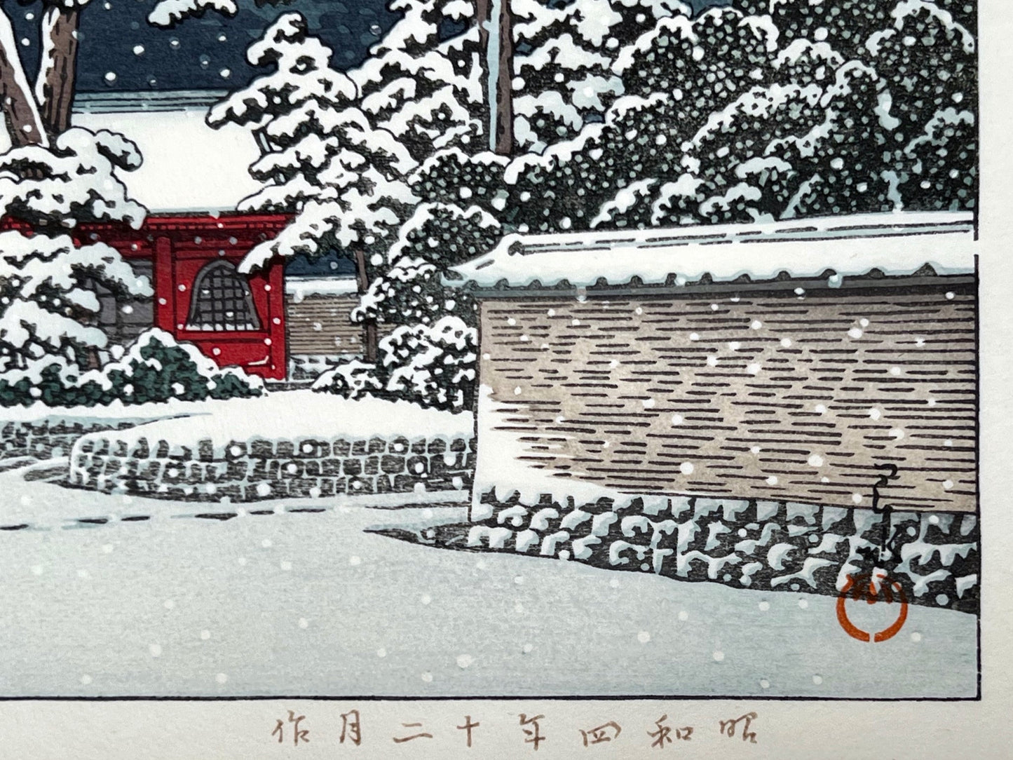 estampe japonaise la neige tombe la nuit sur le temple rouge, un promeneur sous un parapluie avec son chien, signature de l'artiste