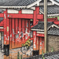 estampe japonaise un personnage à vélo franchit la grande porte rouge d'un temple sous la pluie à Tokyo, gros plan sur l'arche de la porte