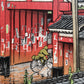 estampe japonaise un personnage à vélo franchit la grande porte rouge d'un temple sous la pluie à Tokyo, détail personnage en ciré vert à vélo