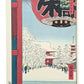 Estampe japonaise de Hiroshige représentant l’entrée du temple Kinryûzan (Sensô‑ji) sous la neige, cadrée par une grande lanterne, avec pèlerins et pagode à Asakusa.